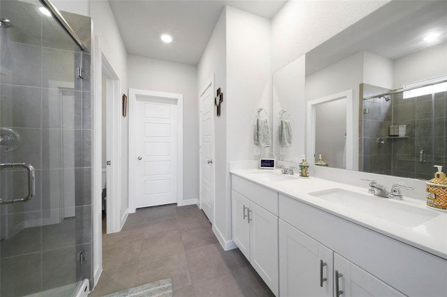 Primary bath with double sinks and large tiled shower with seat