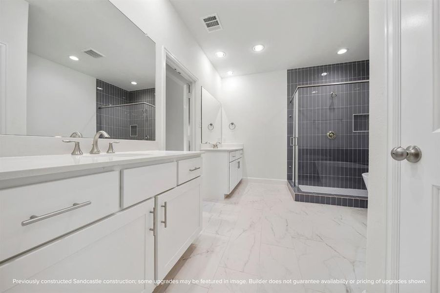 This view showcases the dual vanities and the expansive shower, complemented by a private water closet for added privacy.