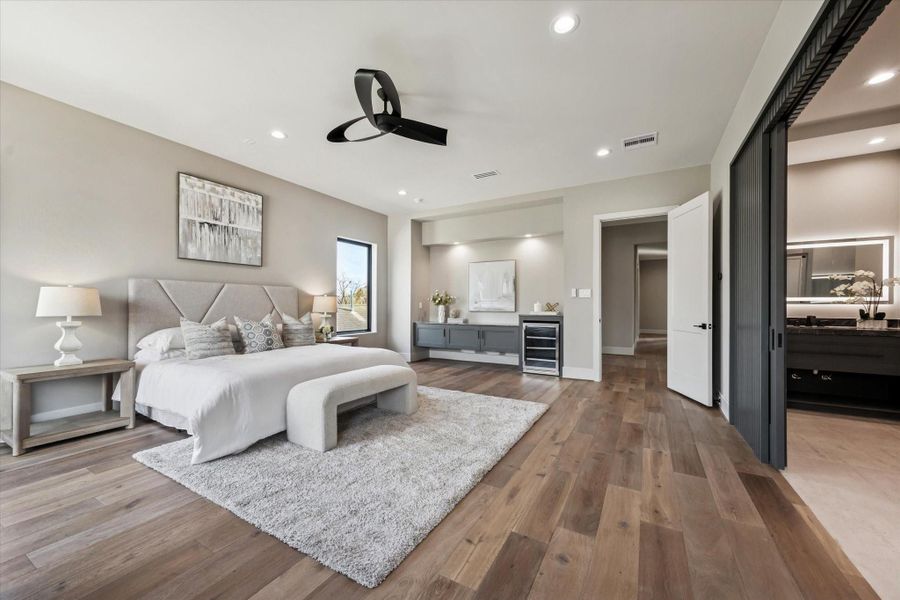 The primary bedroom includes a sleek floating cabinet with quartz countertops, adding both style and functionality to the space. Designed with room for a beverage cooler, it creates a convenient refreshment area that enhances the comfort and luxury of the suite.