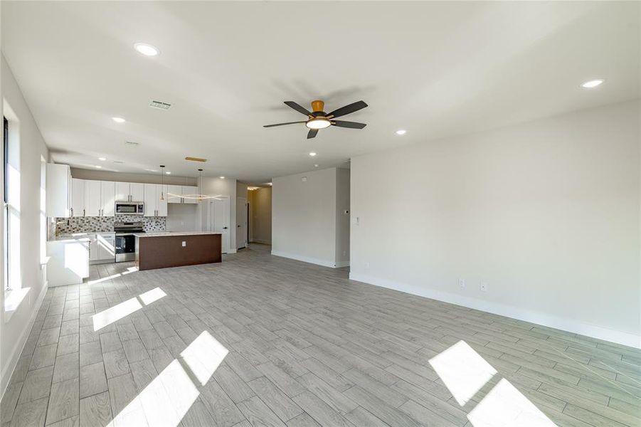 Unfurnished living room with ceiling fan and light wood-type flooring