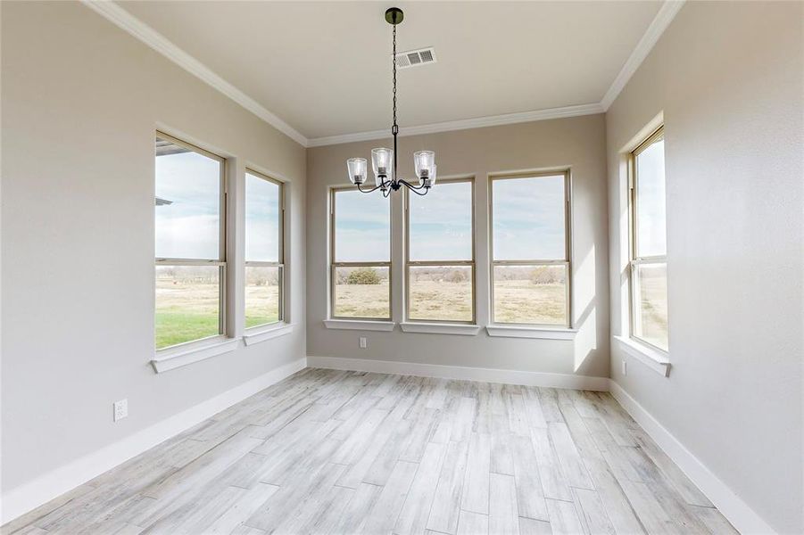 Unfurnished dining area with light hardwood / wood-style floors, ornamental molding, and a chandelier