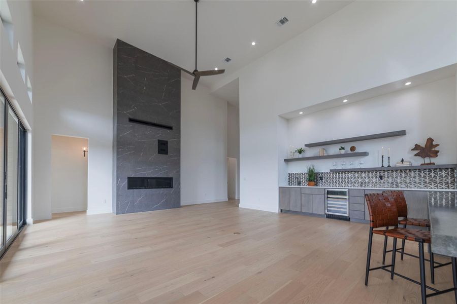 Kitchen with open shelves, a high ceiling, modern cabinets, light wood-type flooring, and beverage cooler