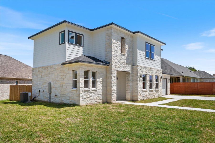 Two-story home with a clean façade, featuring stone and siding, and an inviting grassy lawn.