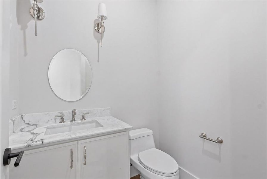 Secondary half bath with marble vanity, dual sconces, and round mirror Secondary half bath with marble vanity, dual sconces, and round mirror