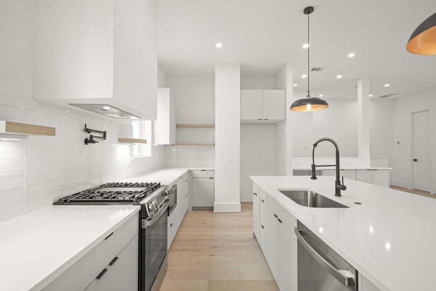 The stainless steel GE appliance package includes a gas range with 4 burners and a griddle, an oversized vent hood and dishwasher. The microwave is located in the lower cabinets.shelves on either side of the expansive kitchen.