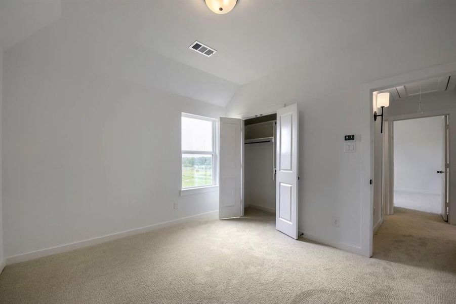 Carpeted interior room featuring a vaulted ceiling and a window with a green landscape Carpeted interior room featuring a vaulted ceiling and a window with a green landscape