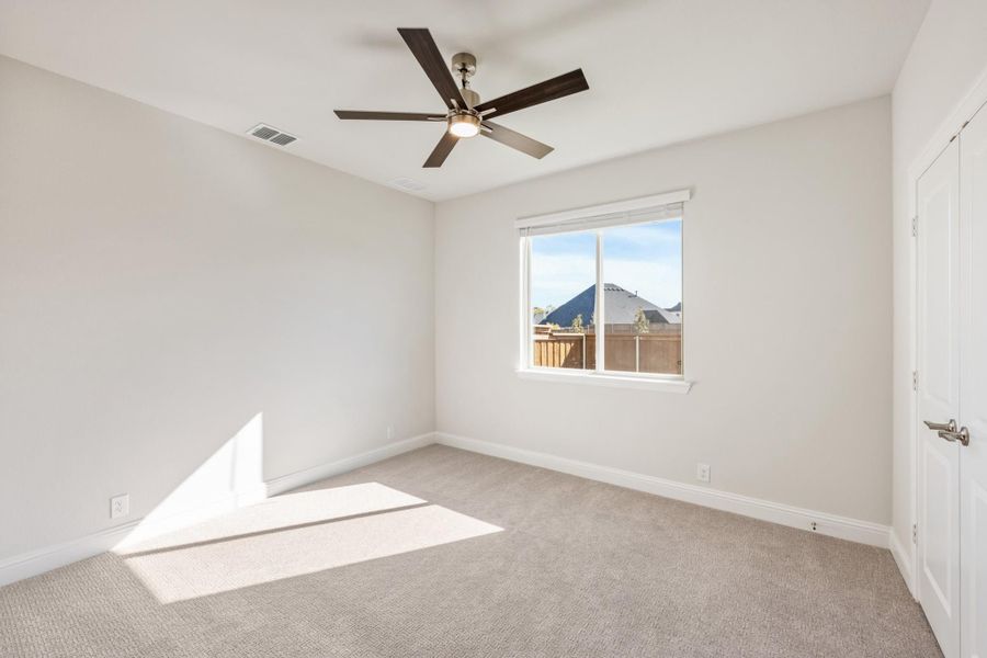 Empty bedroom with beige carpet, ceiling fan, and single window with backyard view Empty bedroom with beige carpet, ceiling fan, and single window with backyard view