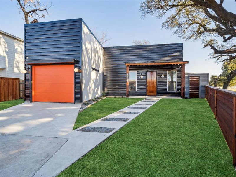 Modern home featuring a front lawn, an outdoor structure, and a garage