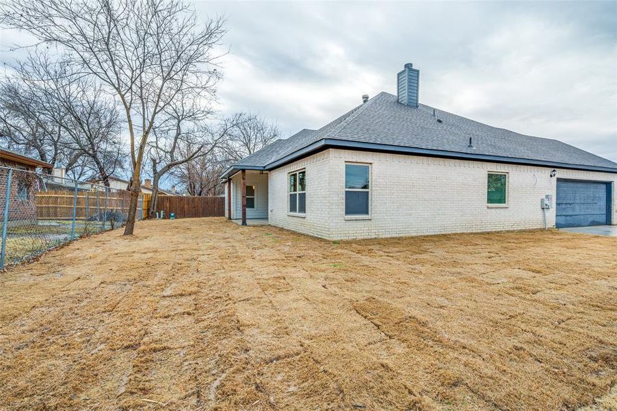 Rear view of house featuring a garage and a yard