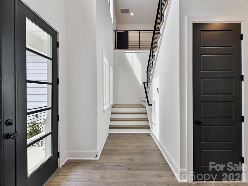 Bright stairway with modern cable railing, sleek black doors, and clean architectural lines leading to the upper level.