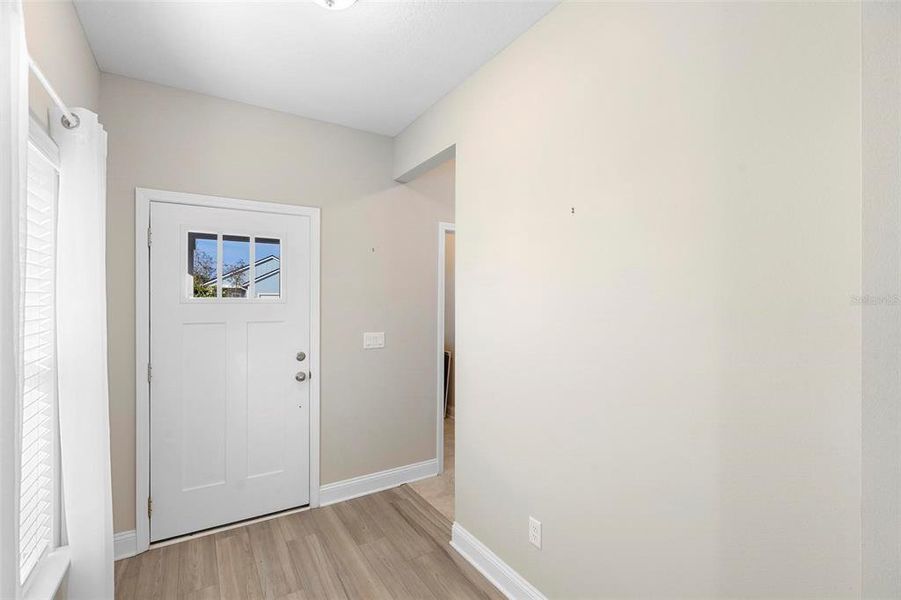 The upgraded entrance door, illuminated with natural light, welcomes you into the heart of the home. To the left, you'll find a private laundry room, offering both convenience and functionality as you step inside.