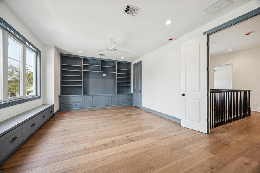 Upstairs game room features custom built ins with lower cabinet storage and a window seat for relaxed movie nights or homework sessions. Designer trim accents and wide plank hardwoods continue the elevated feel throughout the second level.