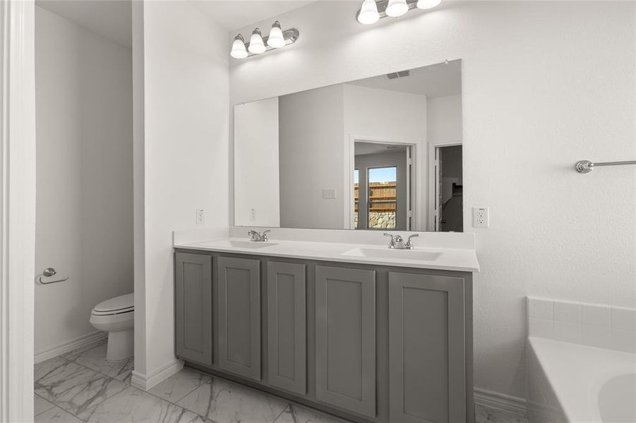 Bathroom with a washtub, vanity, and toilet