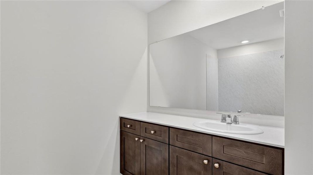 Extended vanity with dark wood-finish cabinetry, a white countertop, and an integrated oval sink
