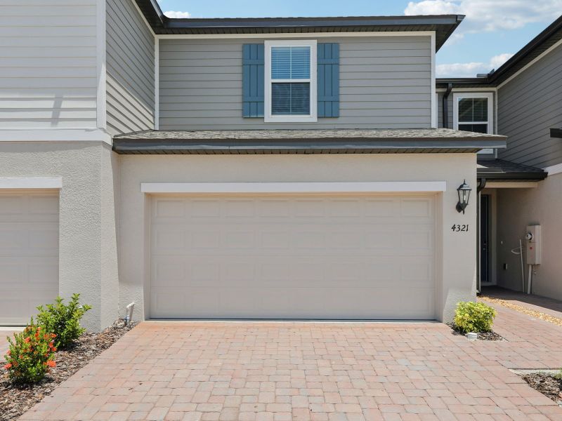 Front exterior of a new home in The Meadow at Crossprairie Townes, St. Cloud, FL, highlighting curb appeal (Image 1). Front exterior of a new home in The Meadow at Crossprairie Townes, St. Cloud, FL, highlighting curb appeal (Image 1).