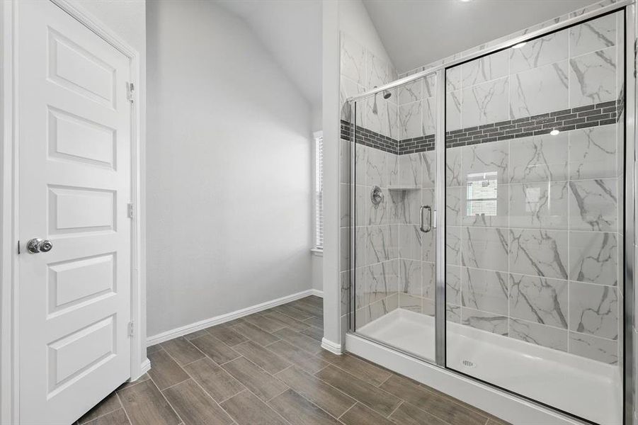 Bathroom featuring a stall shower, vaulted ceiling, and wood finish floors Bathroom featuring a stall shower, vaulted ceiling, and wood finish floors