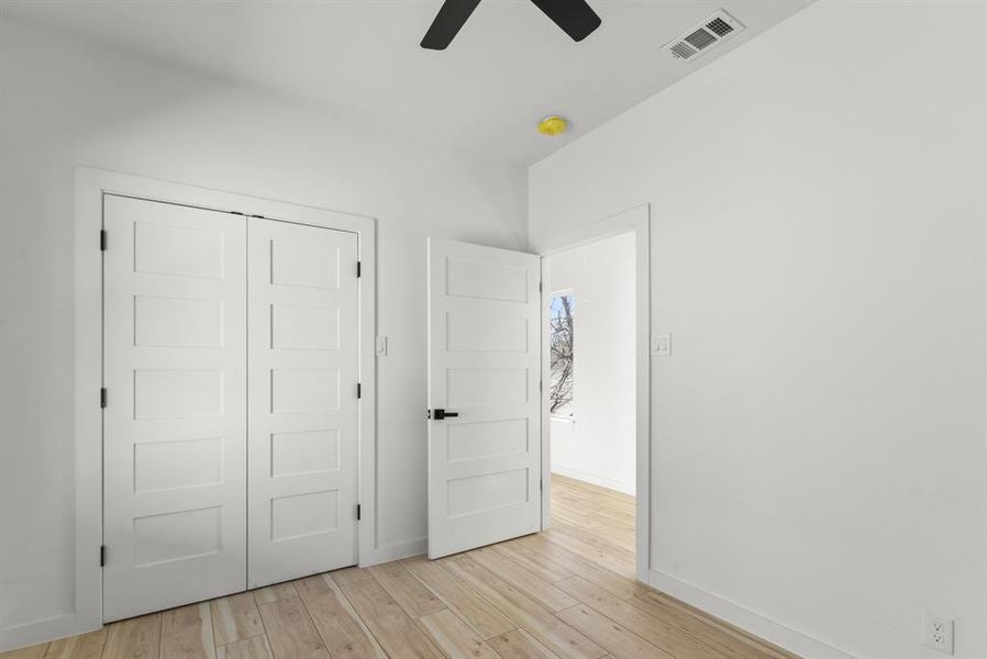 Secondary bedroom with light wood-type flooring, a closet, visible vents, and baseboards