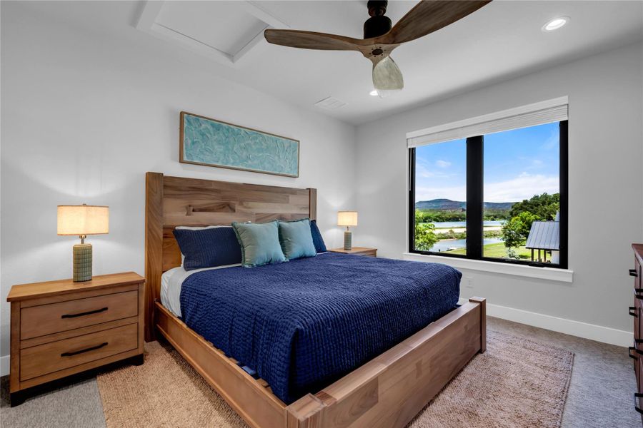 Bedroom four: Expansive window framing a water and distant landscape, wood-finish flooring, recessed lighting, and a contemporary ceiling fan