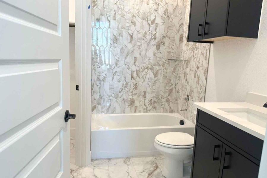 Bathroom with washtub / shower combination, vanity, and light marble finish flooring Bathroom with washtub / shower combination, vanity, and light marble finish flooring