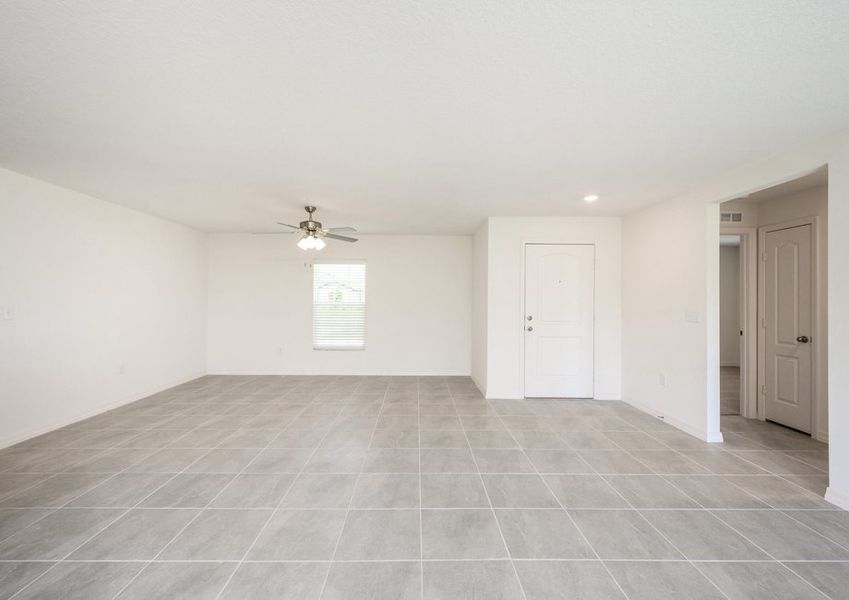 View of the front door from the CaladesiÂ plan's living room that has tile flooring, white walls and recessed lighting.