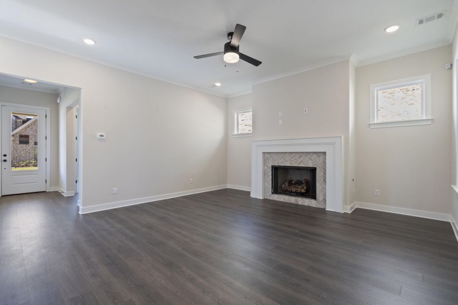 Unfurnished living room with dark wood-type flooring, a fireplace with limestone tile, recessed lighting, a ceiling fan, and crown molding Unfurnished living room with dark wood-type flooring, a fireplace with limestone tile, recessed lighting, a ceiling fan, and crown molding