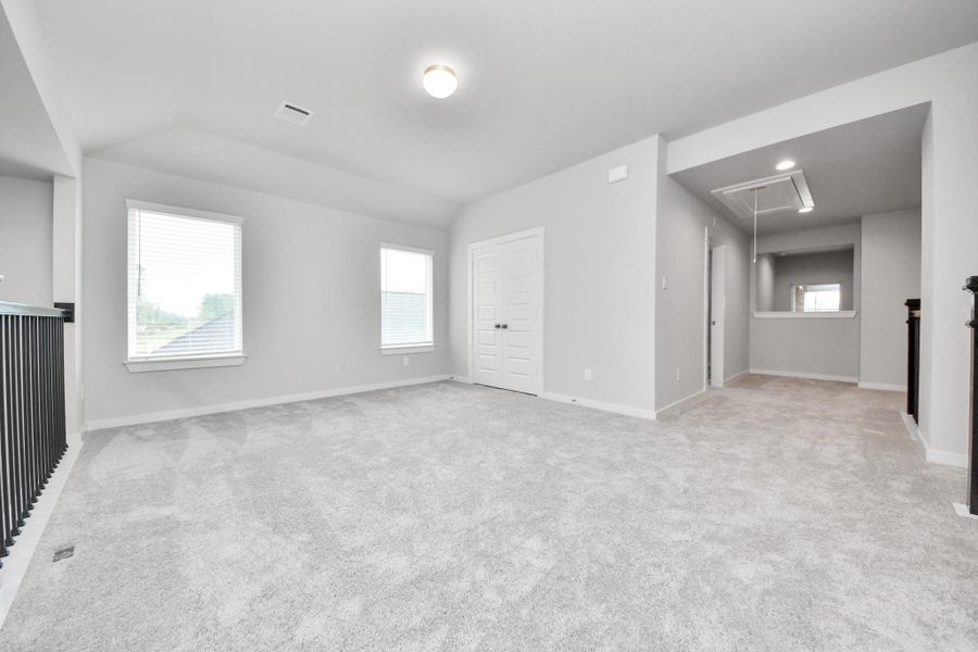 Come upstairs and relish a day of relaxation in this loft area! Ideal as an additional living space or game room, it boasts plush carpeting, high ceilings, custom paint, and windows that flood the area with abundant natural light. Sample photo of completed home with similar floor plan. Actual colors and selections may vary.