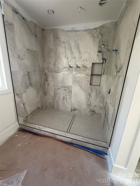 Primary walk-in shower with three shower heads.