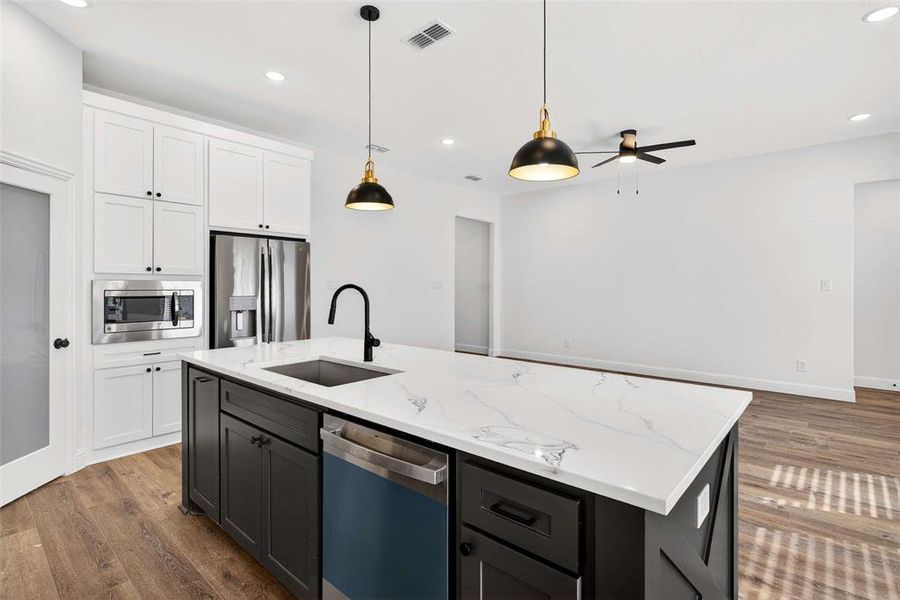 Kitchen featuring white cabinetry, stainless steel appliances, hanging light fixtures, light stone counters, and recessed lighting