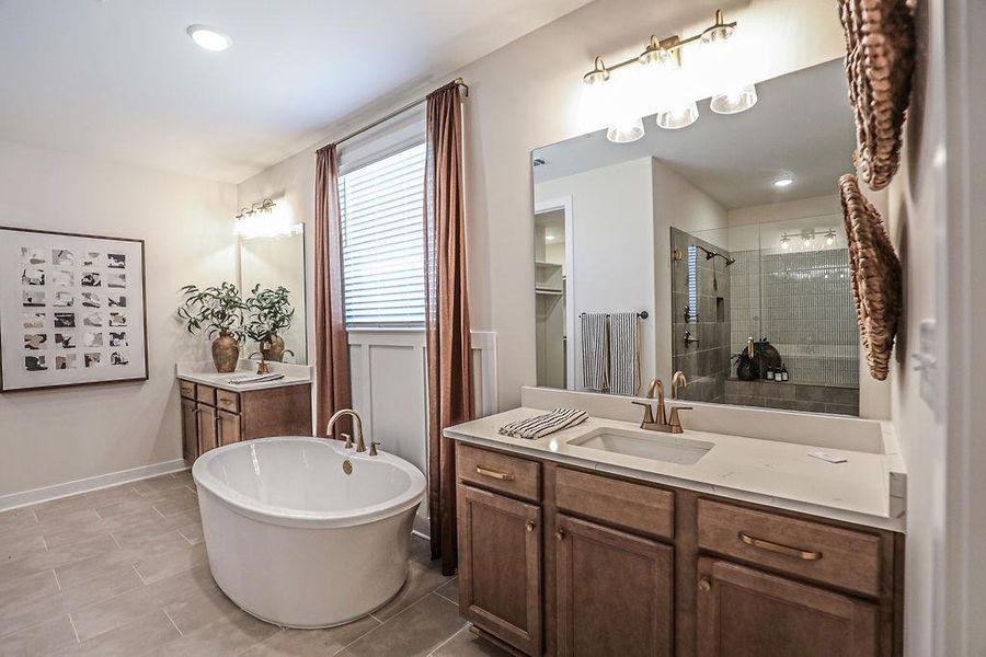 Full bath featuring two vanities, a stall shower, a freestanding bath, and recessed lighting