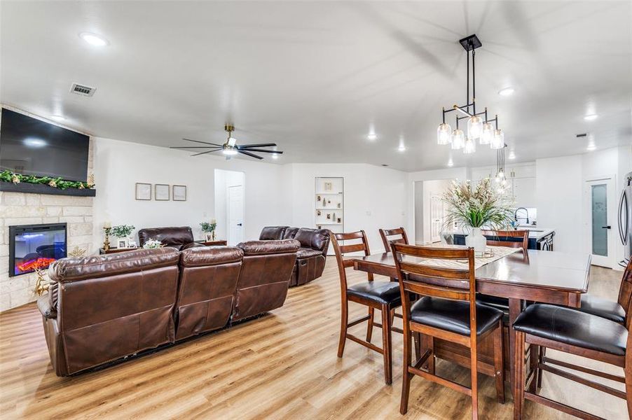 Dining space with recessed lighting, ceiling fan, a stone fireplace, and light wood-style floors