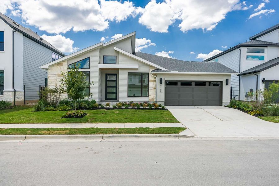 View of front of home with stone siding, driveway, roof with shingles, and a front yard View of front of home with stone siding, driveway, roof with shingles, and a front yard