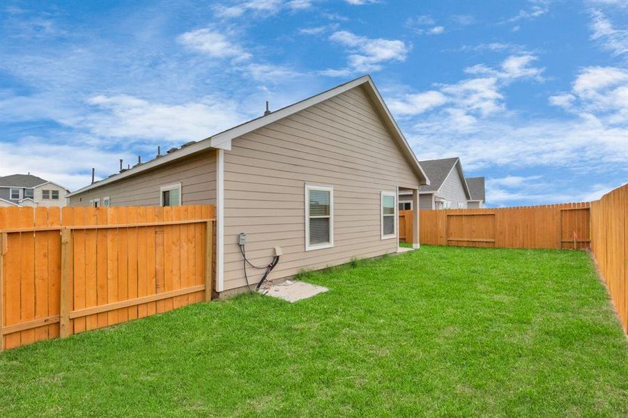 Another angle of this charming backyard reveals more of its well-manicured lawn and secure wooden fencing, providing an ideal private space for relaxation or outdoor entertainment. The gentle slope of the yard and the fenced perimeter ensure safety and privacy, making it an excellent choice for families and pet owners who value outdoor space in a tranquil environment. **This image is from another Saratoga Home - Wren floorplan.**