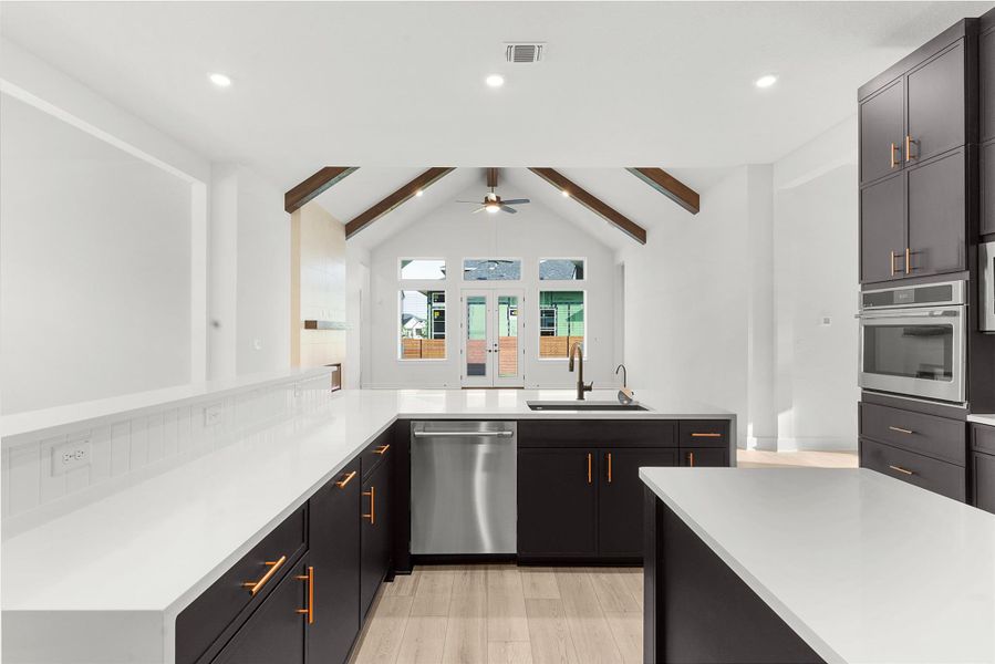 Kitchen featuring appliances with stainless steel finishes, a peninsula, recessed lighting, dark cabinetry, and light wood-type flooring