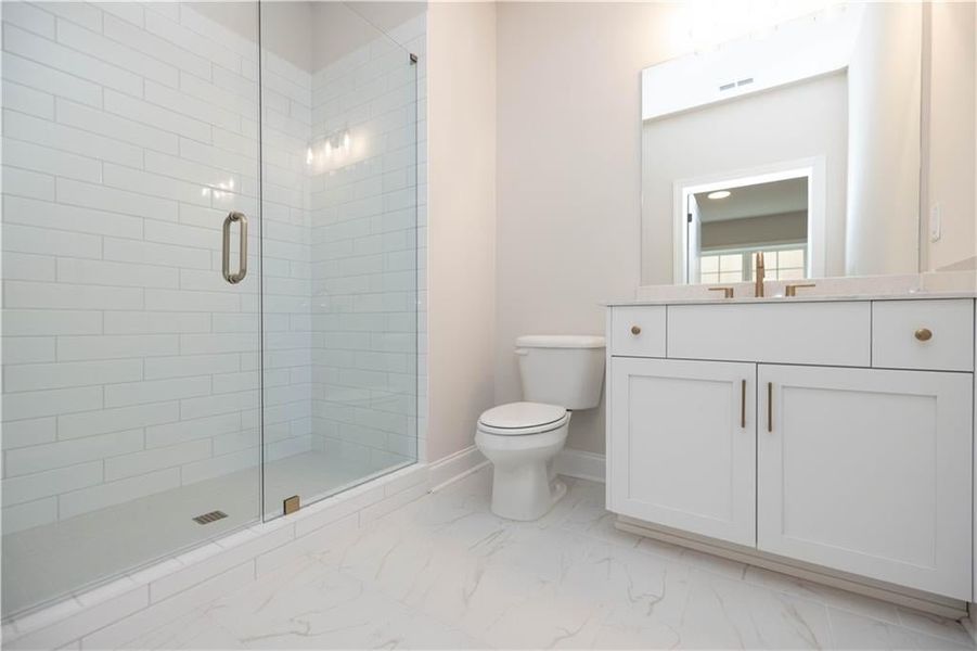 Bathroom with vanity, a shower with shower door, and toilet