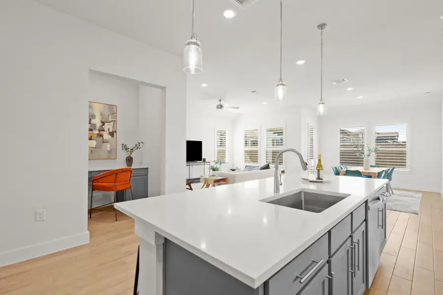 Kitchen featuring hanging light fixtures, gray cabinetry, open floor plan, a kitchen island with sink, and light wood-style flooring