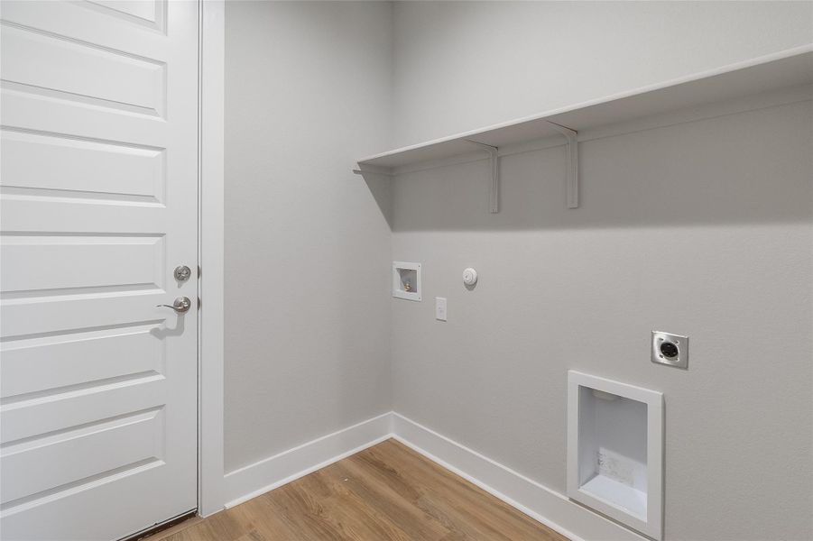 Laundry room with electric dryer/washer hookups, shelving, and door leading to garage Laundry room with electric dryer/washer hookups, shelving, and door leading to garage
