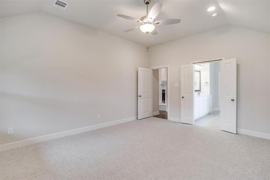 Unfurnished bedroom featuring light carpet, lofted ceiling, and ceiling fan