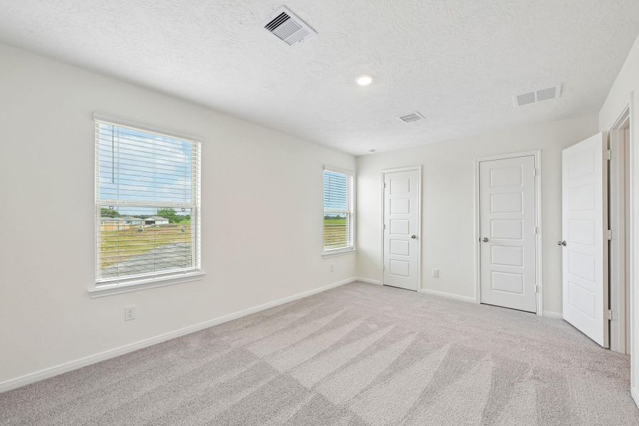 Well appointed secondary bedroom that features plush carpeting, neutral paint tones, recessed lighting, large windows with fitted blinds, and a generously sized closet.