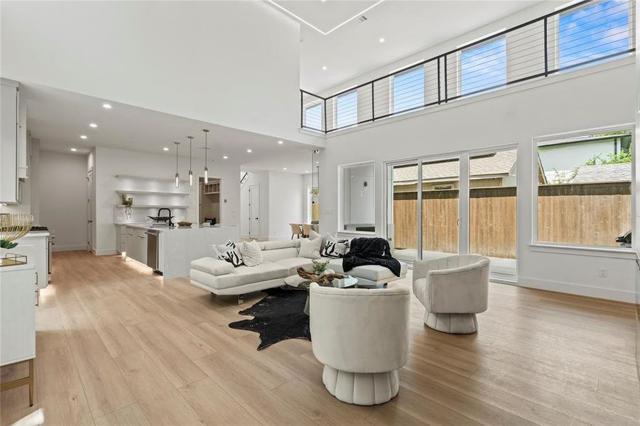 Living room featuring a towering ceiling, light wood finished floors, and recessed lighting