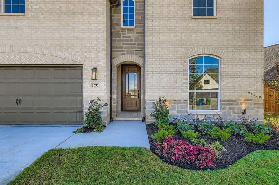 Doorway to property featuring a garage, driveway, and brick siding