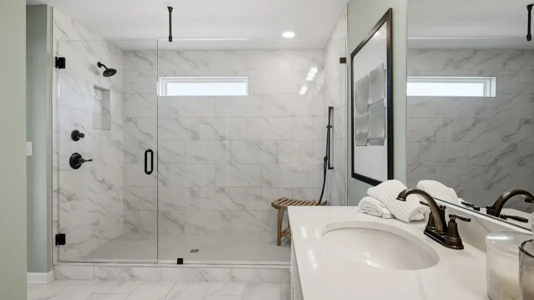 Tile walk-in shower with glass enclosure and modern fixtures in primary bathroom of townhome in Loganville, GA.