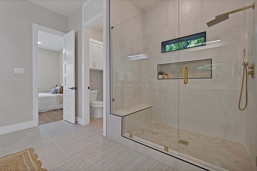 Bathroom featuring toilet, a stall shower, ensuite bath, and baseboards Bathroom featuring toilet, a stall shower, ensuite bath, and baseboards