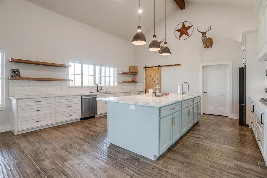 Kitchen featuring white cabinetry, a barn door, dishwasher, and beamed ceiling