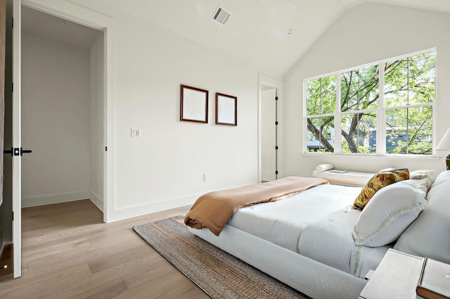 Bedroom featuring multiple windows, lofted ceiling, light wood-style floors, and baseboards