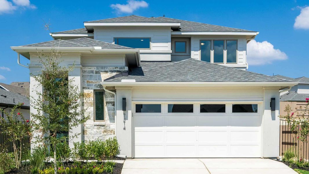 View of front facade featuring stone siding, driveway, an attached garage, and roof with shingles View of front facade featuring stone siding, driveway, an attached garage, and roof with shingles