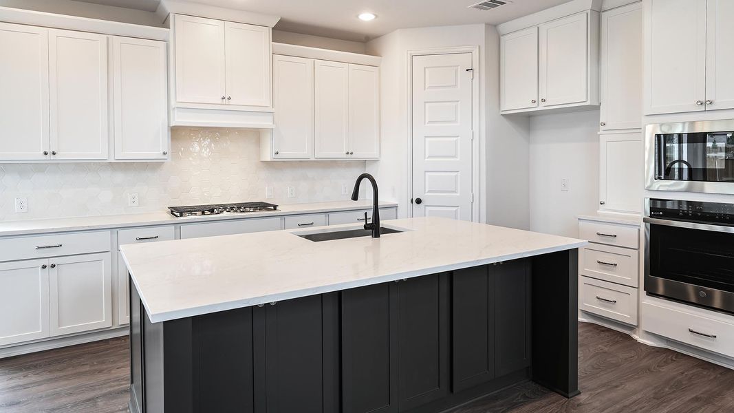Kitchen with appliances with stainless steel finishes, dark wood finished floors, light stone countertops, backsplash, and white cabinetry