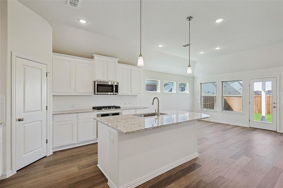 Kitchen featuring appliances with stainless steel finishes, white cabinetry, sink, and an island with sink