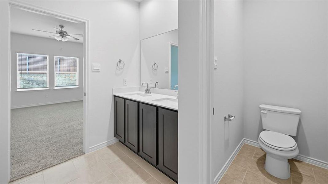 Bathroom featuring light colored carpet, double vanity, ceiling fan, and light tile patterned floors