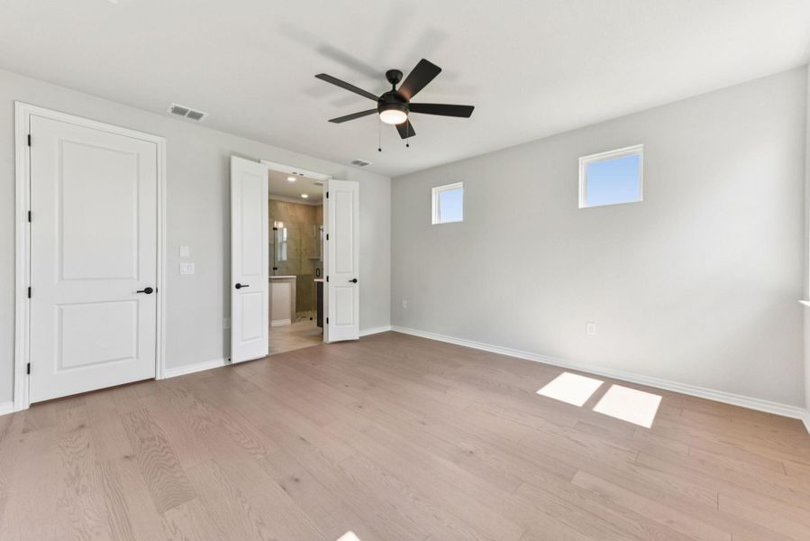 Unfurnished bedroom featuring connected bathroom, light wood-style flooring, and ceiling fan