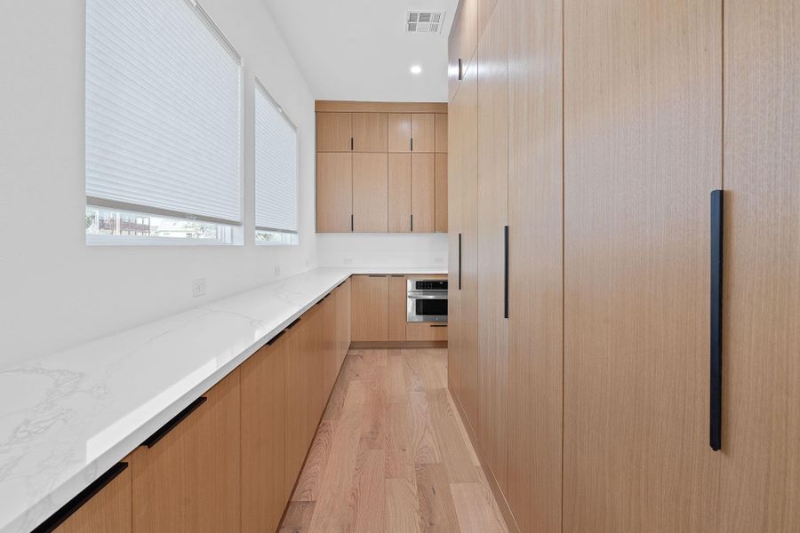 Sleek custom cabinetry lines the back kitchen wall, designed for hidden storage and a clean, modern look. Tons of storage. Sleek custom cabinetry lines the back kitchen wall, designed for hidden storage and a clean, modern look. Tons of storage.
